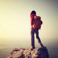 Solo female traveller at the top of a mountain in hiking gear looking out at the view