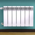 Wall mounted radiator on turquoise pained wall.