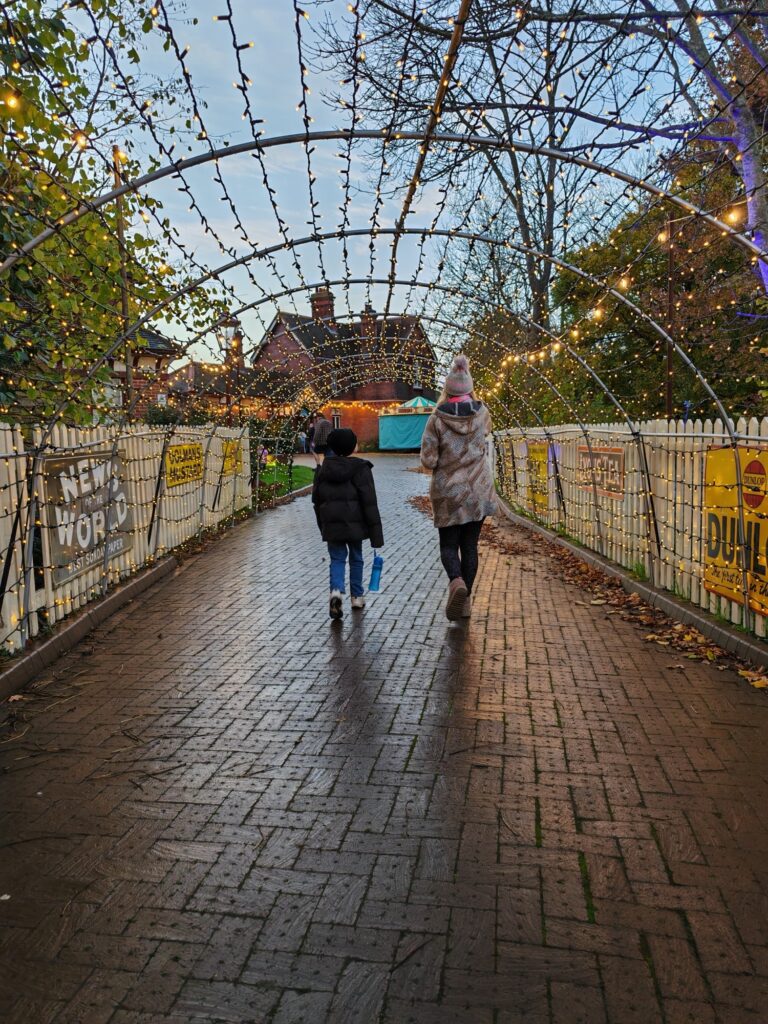 Mum and son walking through the lit tunnel to Sheffiled Park Bluebell Railway train station