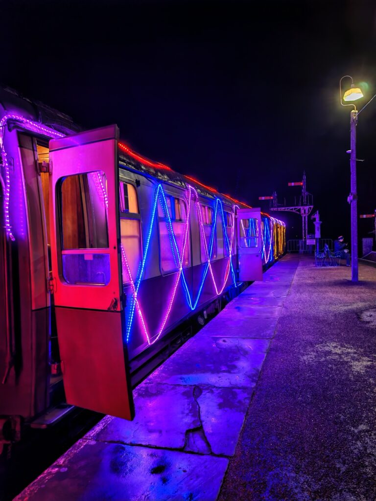 The steamlight train running at Christmas for the Bluebell Railway lit in pink and blue