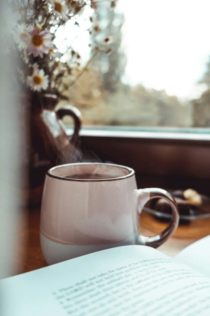 Mug of coffee by a book with view out to the garden