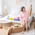 Displeased young woman with clothes in bedroom