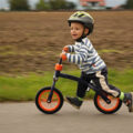 Young child zooming along on a balance bike with helmet