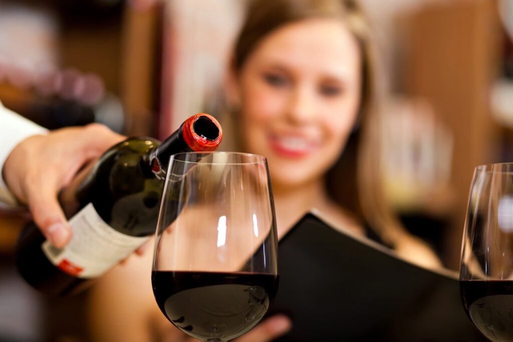 Woman at restaurant pouring glass of red wine