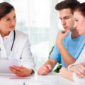 A couple looking anxious discussing their fertility options with a doctor at a fertility clinic.
