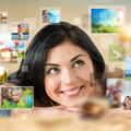 Woman resting her head on her hands whilst looking up and smiling at family photos floating around to represent storing digital images