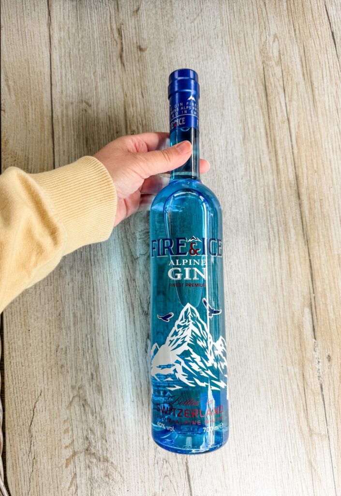 Woman's hand holding a bottle of Fire & Ice Alpine Blue Gin
