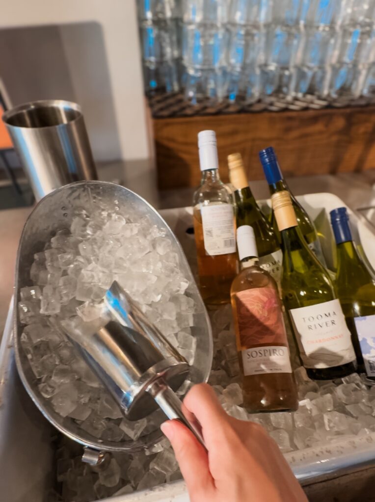 Hand scoping ice with the complimentary wines next to ice bucket at My Lounge at Gatwick airport airport lounges