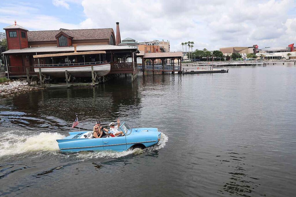 A blue amphicar in the lake outside the boathouse at Disney Springs