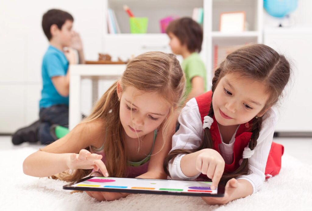 Two girls in a classroom looking at a tablet