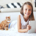 Happy girl with her kitten watching her ipad ay home