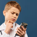 Young boy reading the news on his mobile phone