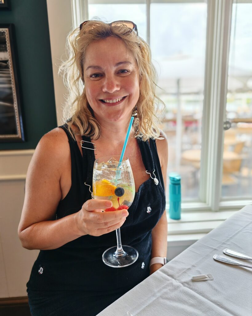 A happy smiling lady with a white wine sangria at the boathouse