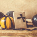 Halloween gifts wrapped up in brown paper and black ribbon with a pumpkin and black balloons