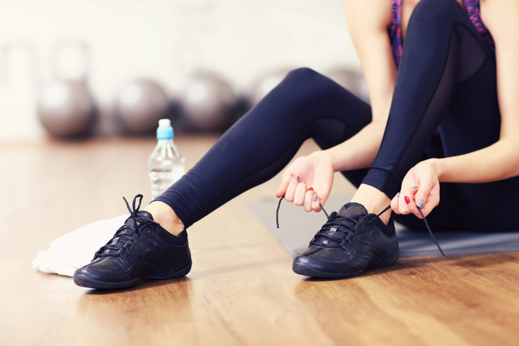 The legs of a lady in the gym tying up her trainers