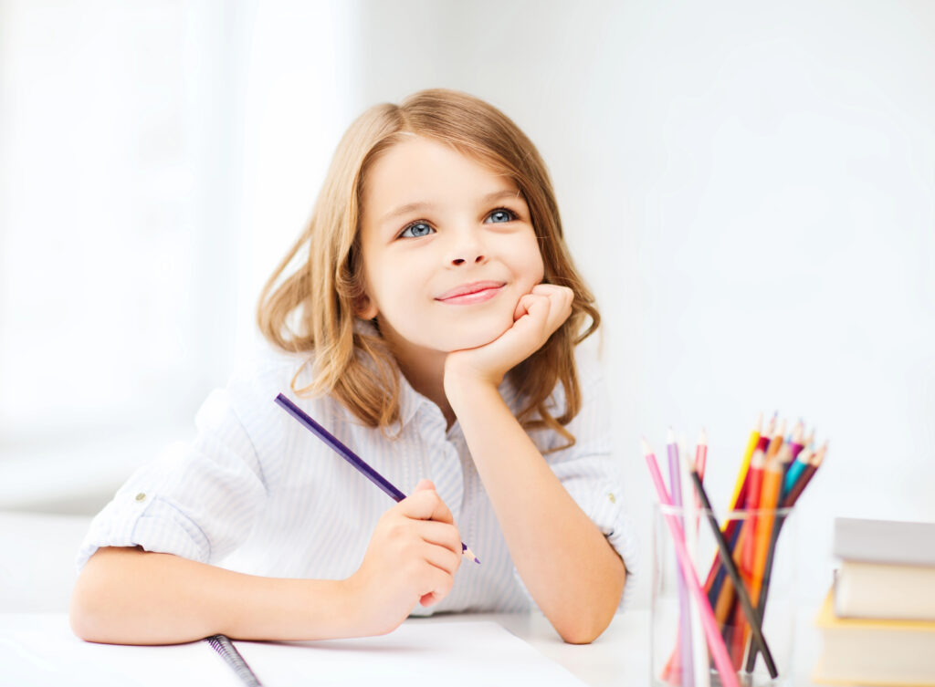Young school girl in school uniform sitting at her desk looking happy and dremaing