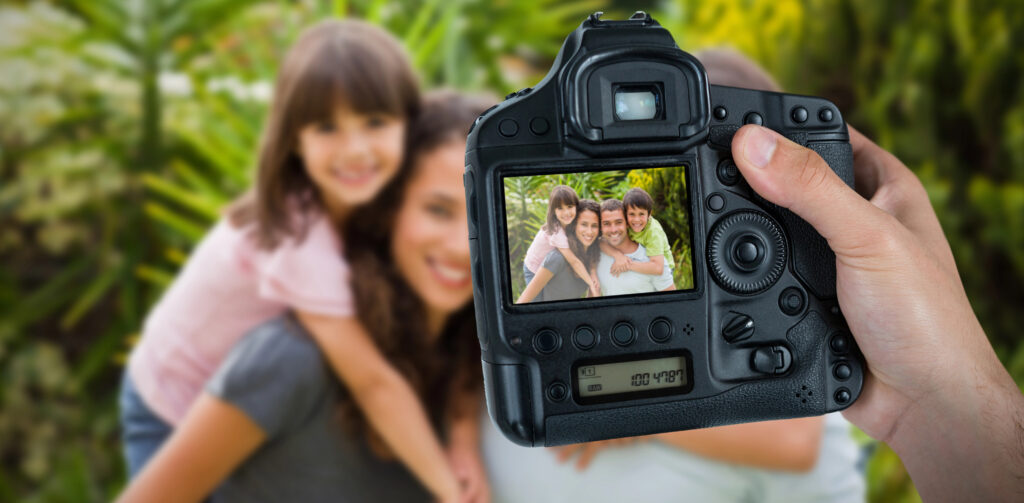someone taking a picture of a family with camera main focus and daughter and mother in the background