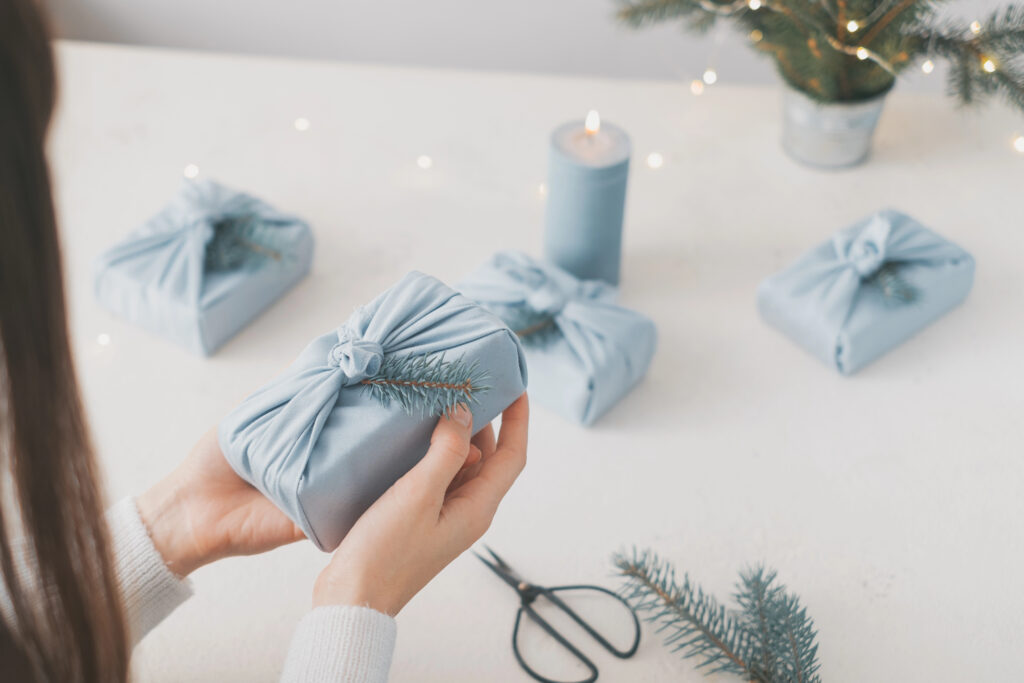 Ladies hand wrapping gifts in blue material for sustainable wrapping