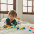 Young child on bed playing with bright educational toys