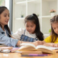 Two asian girls studying at the table with their private tutor