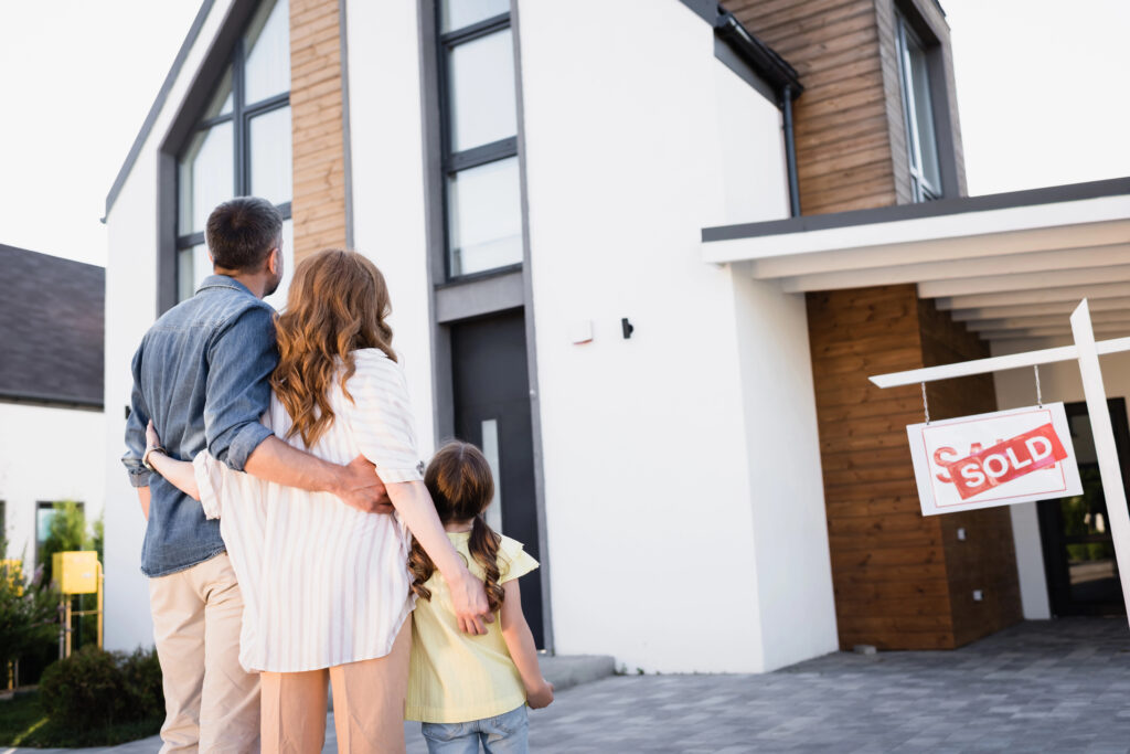 Family looking at a house that has a sold sign in front of it