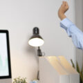 Lady sitting at her home desk working and having a stretch to relieve tension in her back.
